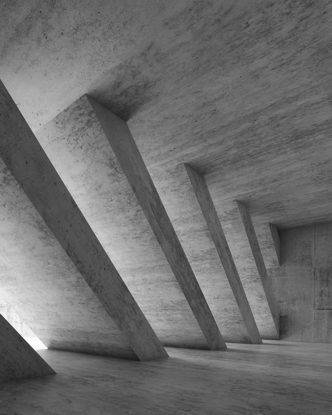 Light falling across the columns of a long concrete hallway, in black and white.