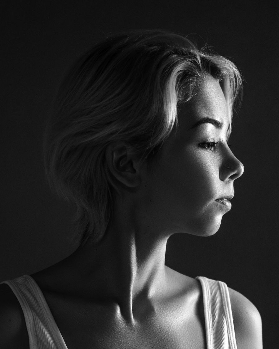 A woman in profile, looking to the side, lit from one window, in black and white.